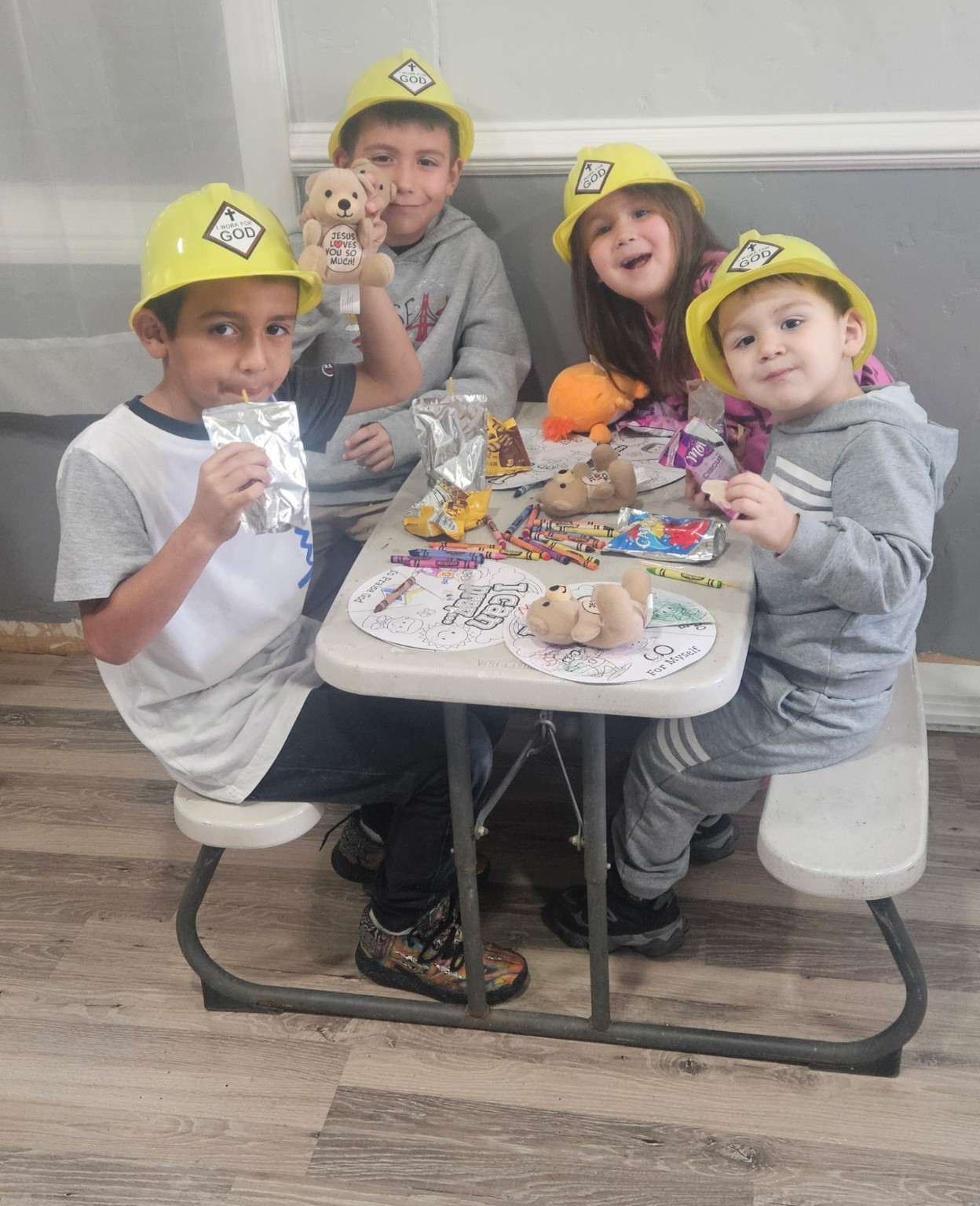 Children in Sunday school wearing 'I work for God' hats
